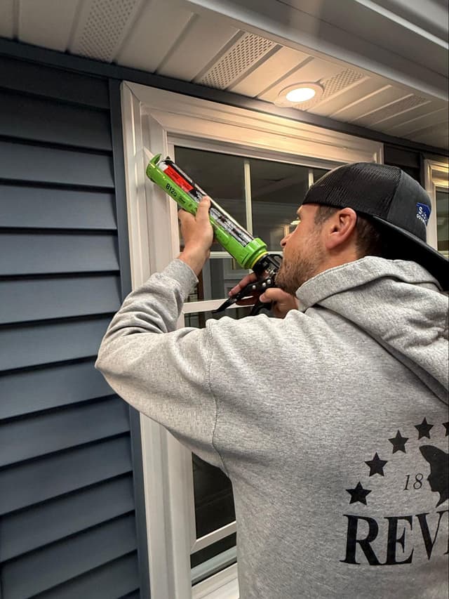 Window installer applying flashing and insulation around new window frame